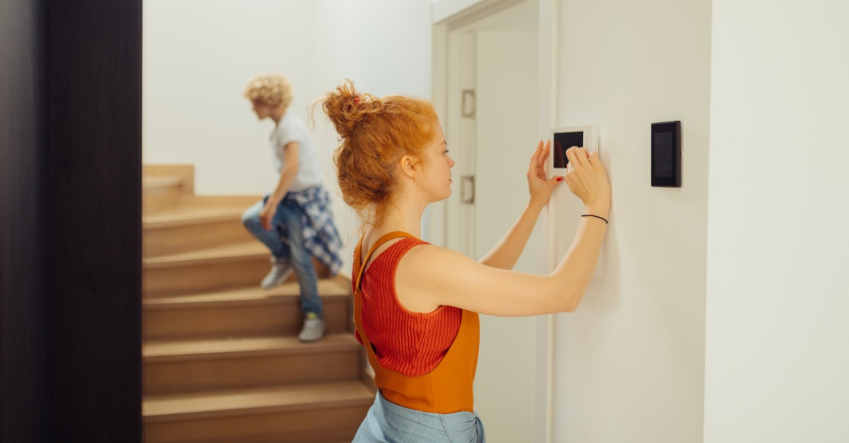 woman standing touching thermostat